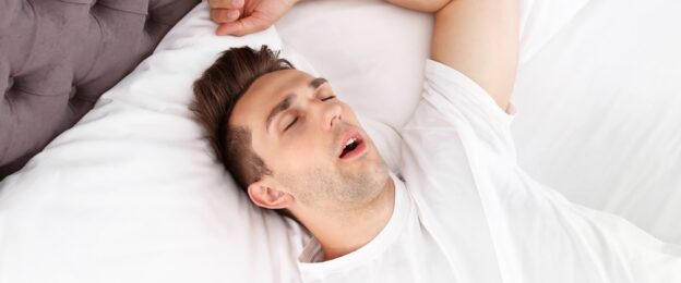 Man sleeping with mouth open and arm above head
